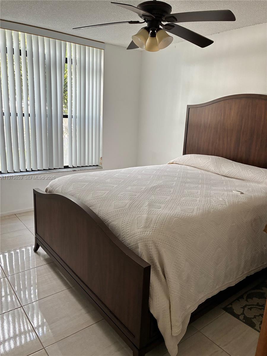 3680 Inverrary Drive, Unit 1T Lauderhill, FL 33319 - Photo 7 of 14 a bedroom with a bed and a chandelier