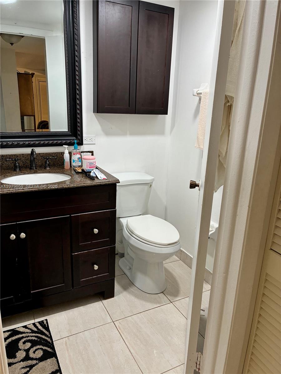 3680 Inverrary Drive, Unit 1T Lauderhill, FL 33319 - Photo 9 of 14 a bathroom with a toilet a sink and a mirror