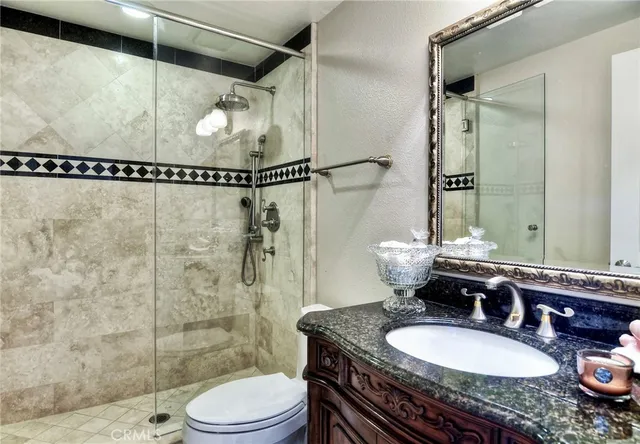 a bathroom with a granite countertop sink toilet a mirror and shower