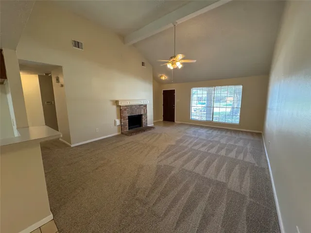 a view of an empty room with window and fireplace
