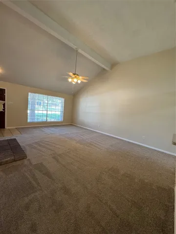 an empty room with chandelier fan and windows