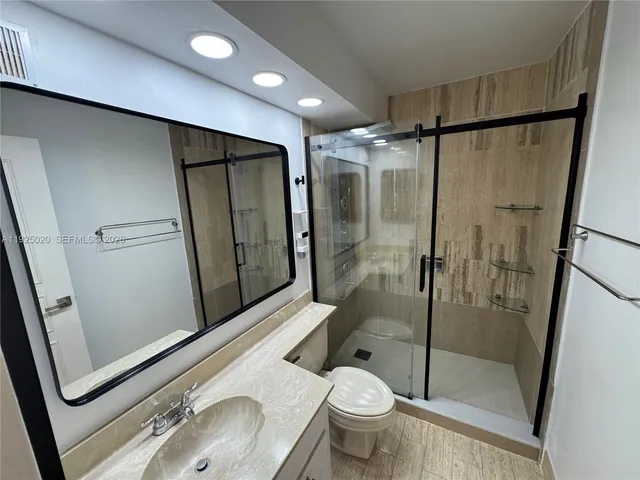 a bathroom with a granite countertop sink toilet and shower