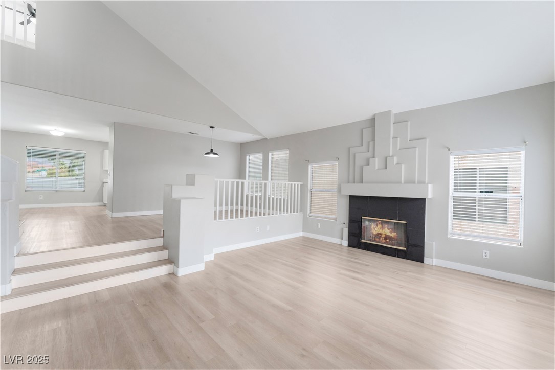 3695 Funston Way Las Vegas, NV 89129 - Photo 15 of 43 Unfurnished living room featuring high vaulted ceiling, light wood-style floors, and a fireplace