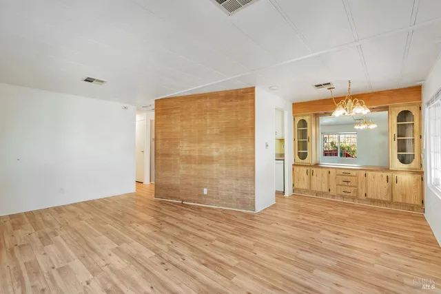 a view of an empty room with window and wooden floor