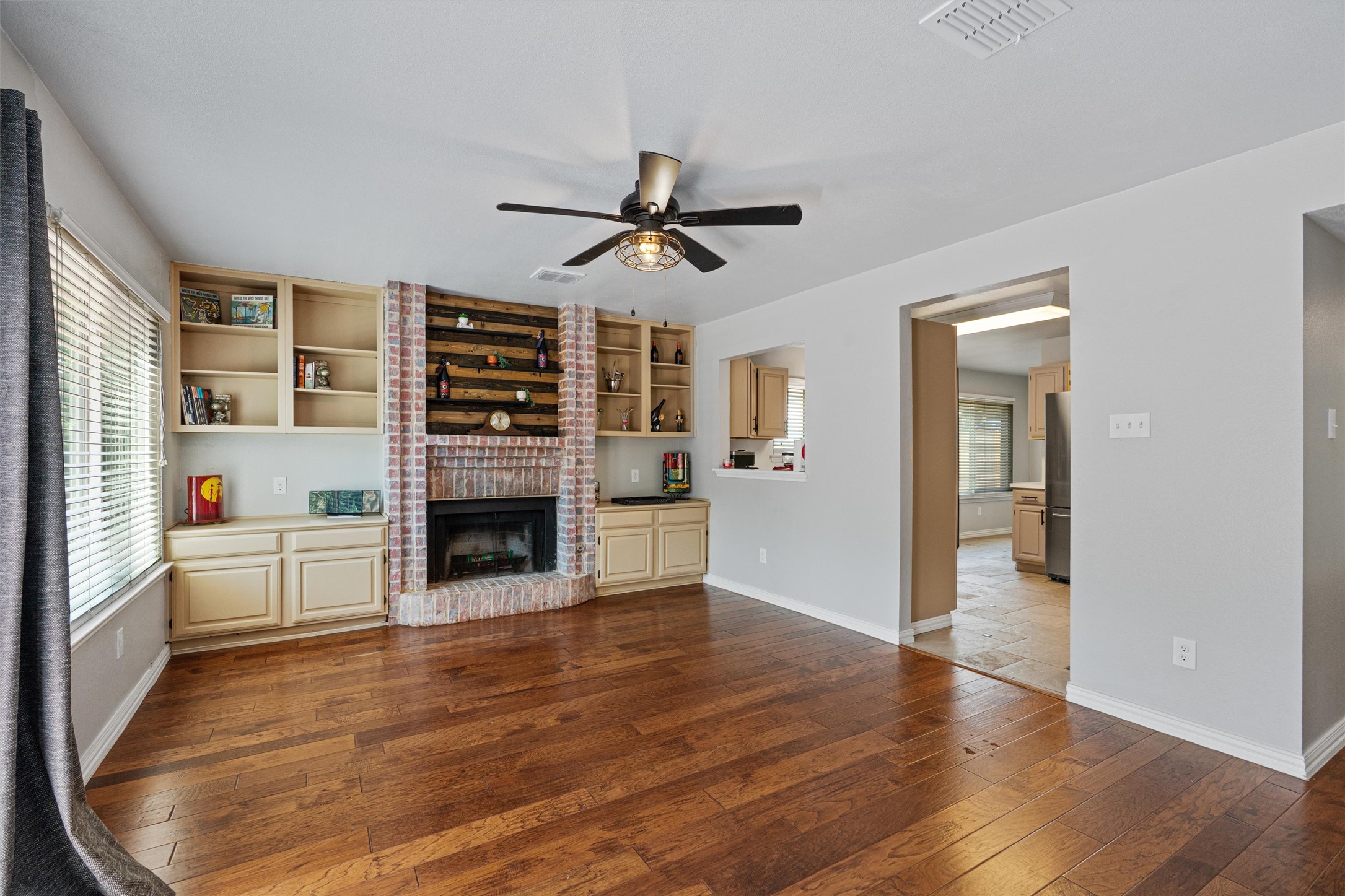 3011 Wadsworth Way Austin, TX 78748 - Photo 10 of 28 a view of a livingroom with a fireplace a ceiling fan wooden floor and windows