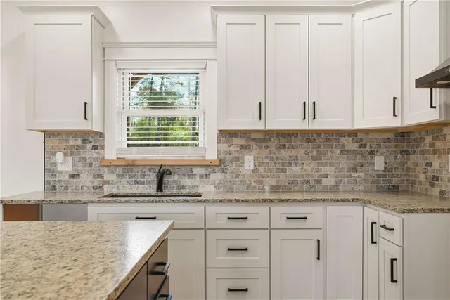 a kitchen with granite countertop white cabinets and window