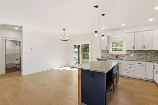 a kitchen with kitchen island granite countertop a stove a sink a center island and cabinets