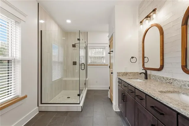 a bathroom with a granite countertop sink a mirror and a shower