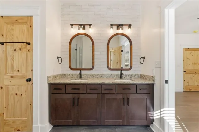 a bathroom with a granite countertop double vanity sink and a mirror