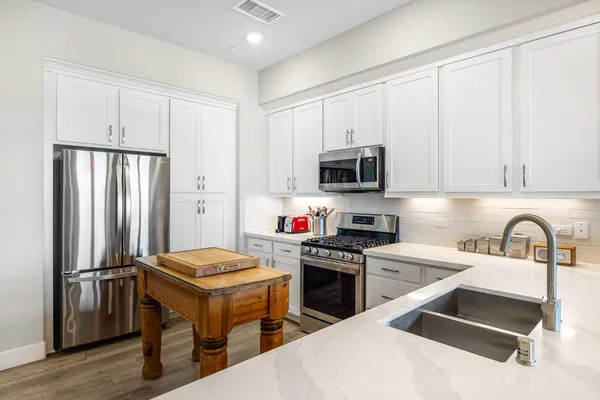 a kitchen with a sink a stove and white cabinets
