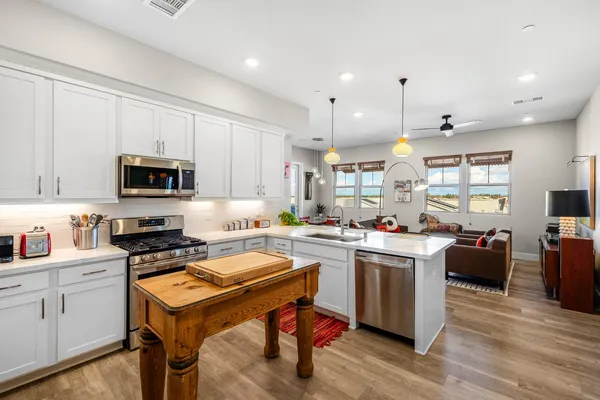 a kitchen with stainless steel appliances a stove a sink a refrigerator and white cabinets