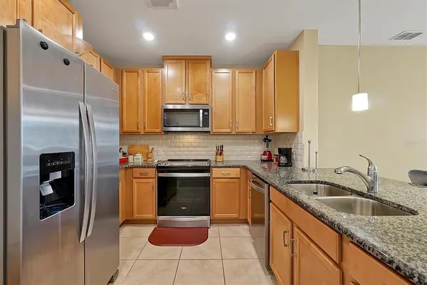 a kitchen with stainless steel appliances granite countertop a refrigerator sink and stove