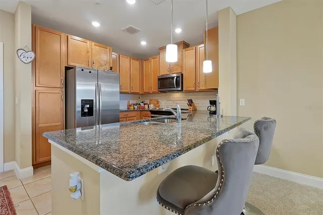 a kitchen with stainless steel appliances granite countertop a sink refrigerator and cabinets