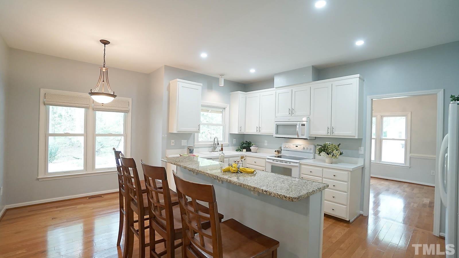 10721 Durant Road Raleigh, NC 27615 - Photo 10 of 37 a kitchen with a dining table chairs sink and cabinets