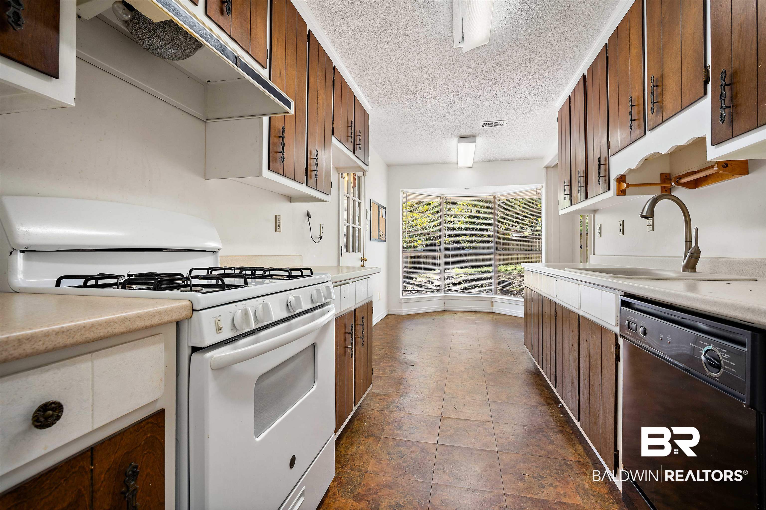 5559 Woodside Drive North Mobile, AL 36608 - Photo 23 of 28 Kitchen featuring white range with gas cooktop, under cabinet range hood, light countertops, dishwasher, and a textured ceiling