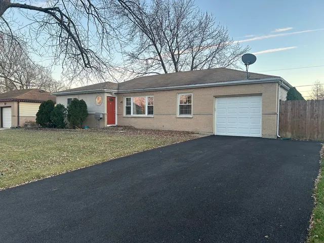 a front view of house with yard and trees in the background