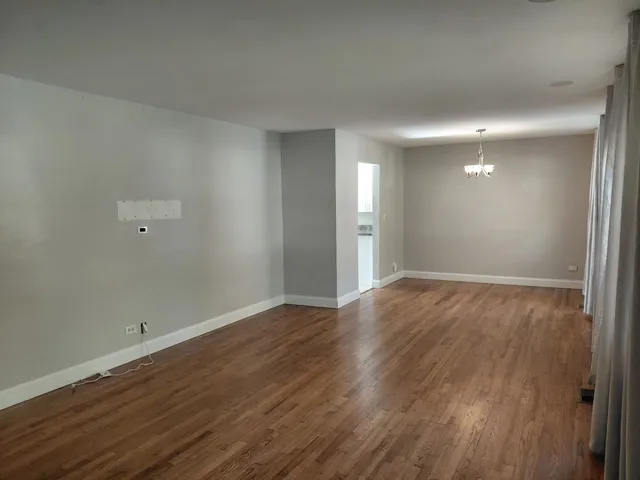 a view of an empty room with wooden floor and closet