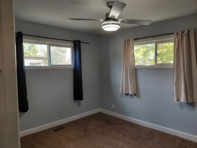 an empty room with windows and fan