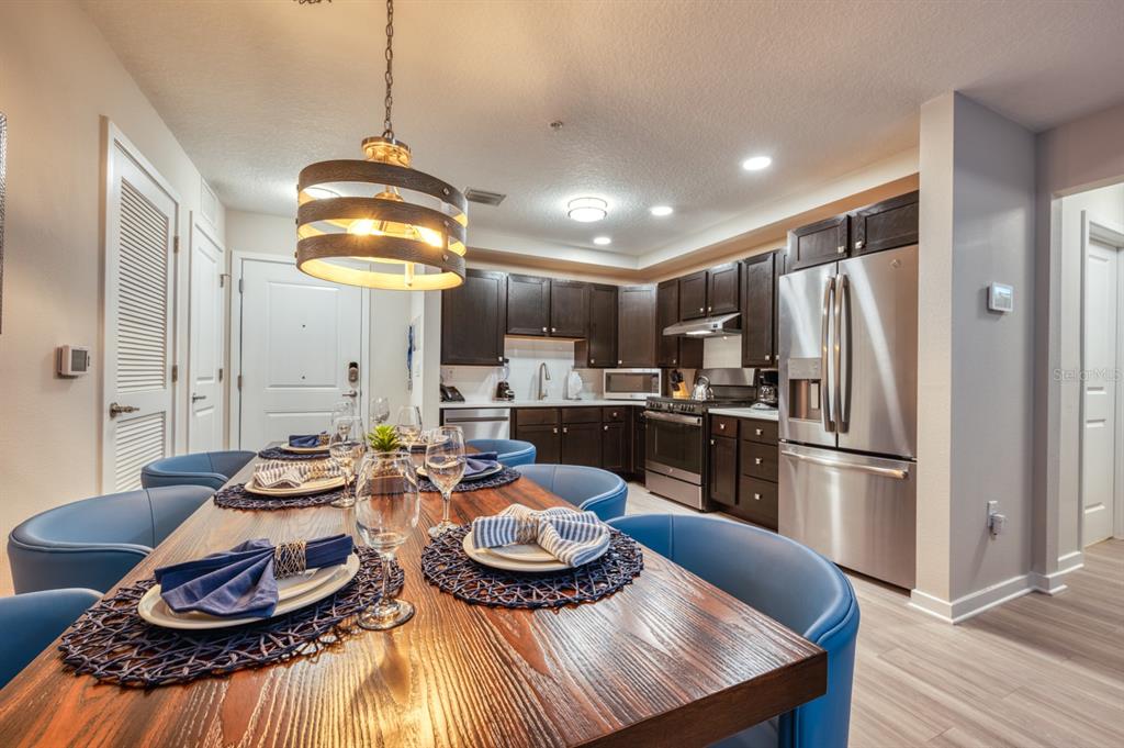 4013 Breakview Drive, Unit A407 Orlando, FL 32819 - Photo 6 of 32 a kitchen with stainless steel appliances kitchen island granite countertop a refrigerator a stove a dining table and chairs with wooden floor