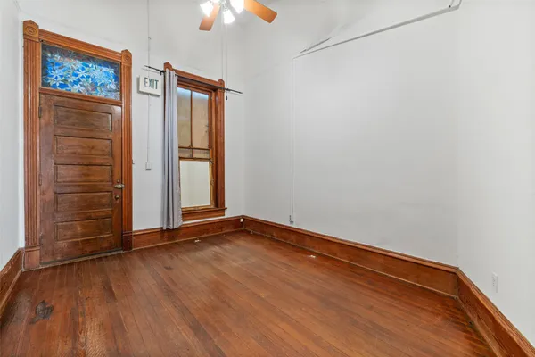 an empty room with wooden floor closet and windows