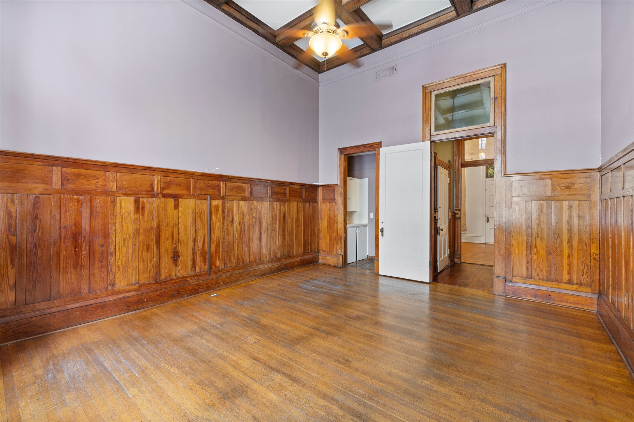 109 East 10th Street Austin, TX 78701 - Photo 7 of 38 Empty room featuring coffered ceiling, wooden walls, a wainscoted wall, dark wood-style flooring, and ceiling fan