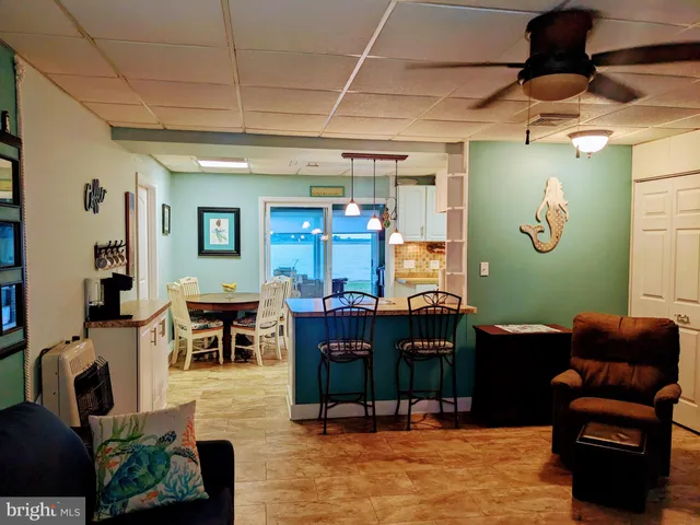 a kitchen with kitchen island granite countertop a stove a sink a dining table and chairs with wooden floor