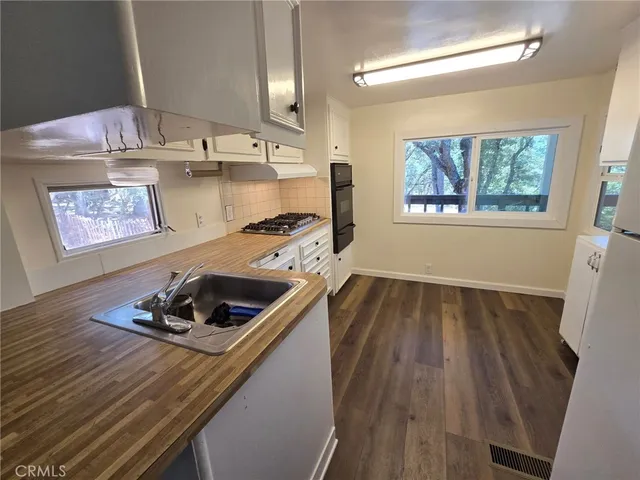 a room with kitchen island white cabinets stove and sink