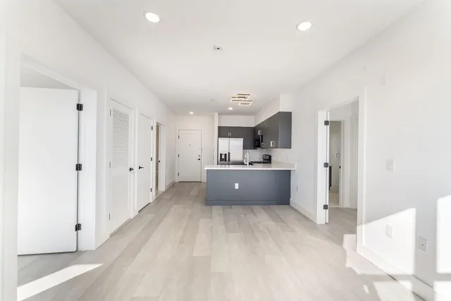 a view of a kitchen with stainless steel appliances kitchen island a sink and a refrigerator