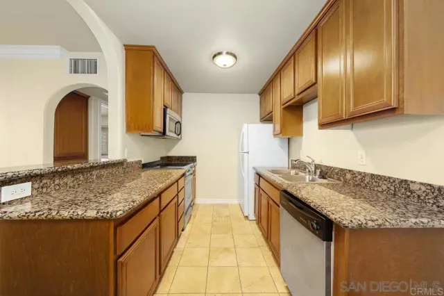 a kitchen with stainless steel appliances granite countertop a sink and a refrigerator