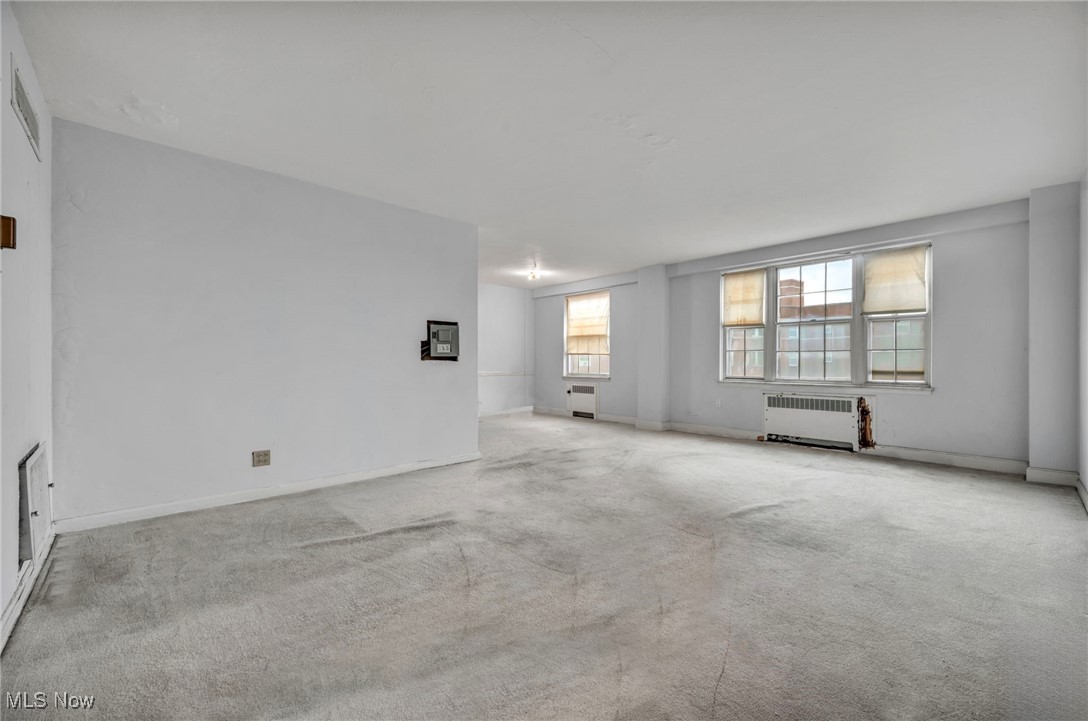 Carpeted empty room featuring radiator