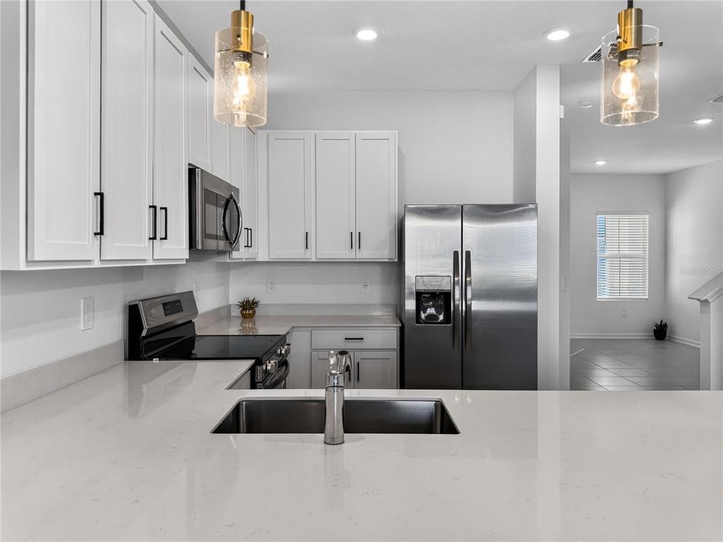 2735 Skyline Loop Kissimmee, FL 34758 - Photo 9 of 33 a kitchen with stainless steel appliances granite countertop a refrigerator a sink a stove and white cabinets