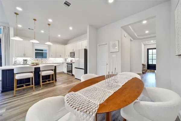 a living room with stainless steel appliances furniture a dining table and kitchen view