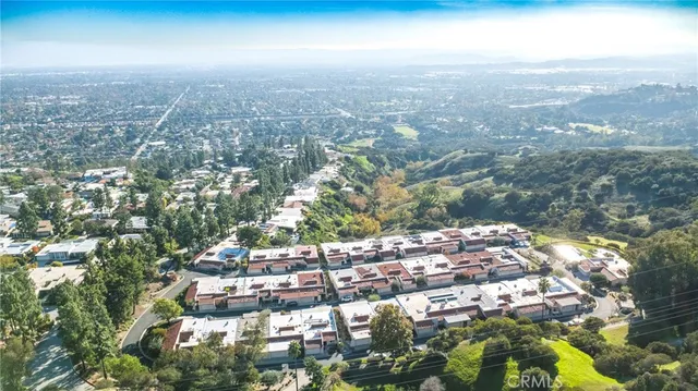 an aerial view of a large building with a large tree and wooden fence