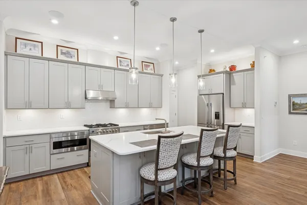 a kitchen with stainless steel appliances kitchen island a table chairs refrigerator and microwave