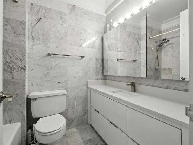 a bathroom with a granite countertop toilet a sink and a shower