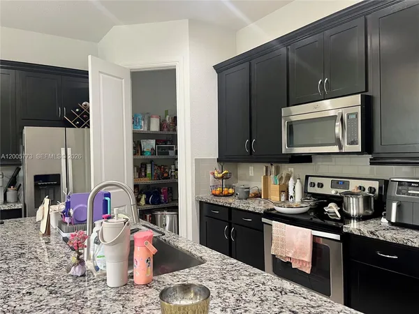 a kitchen with stainless steel appliances granite countertop a sink stove and microwave with wooden floor
