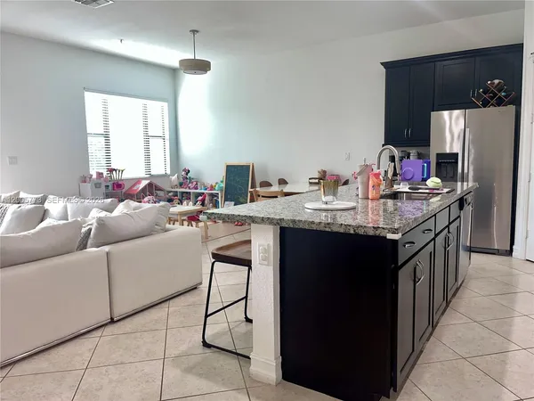 a kitchen with stainless steel appliances granite countertop a sink dishwasher a refrigerator and a dining table with the living room view