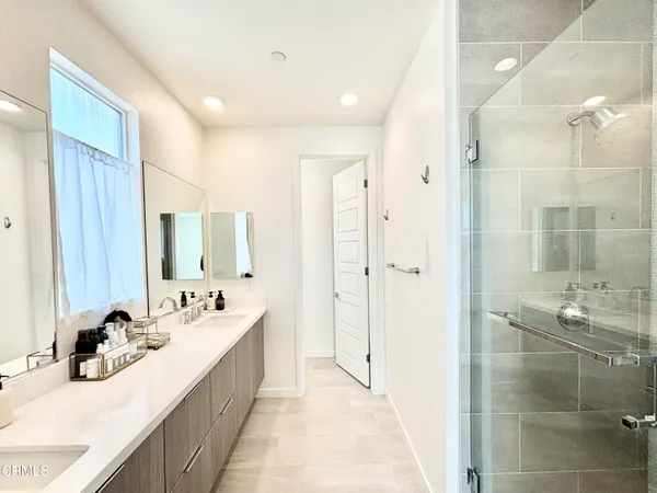 a bathroom with a double vanity sink mirror and shower