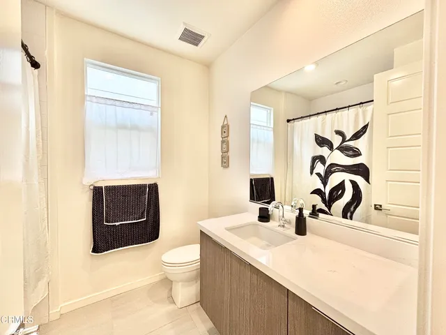 a bathroom with a granite countertop toilet sink and mirror