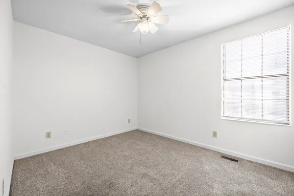 an empty room with a window and a fan