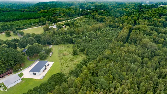 an aerial view of residential house with outdoor space and trees all around