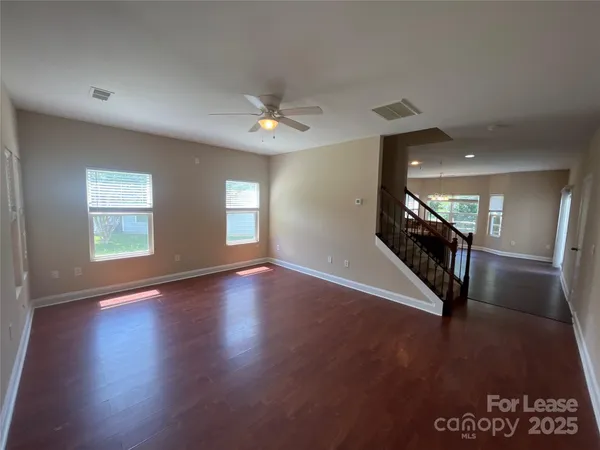 a view of a livingroom with wooden floor and stairs