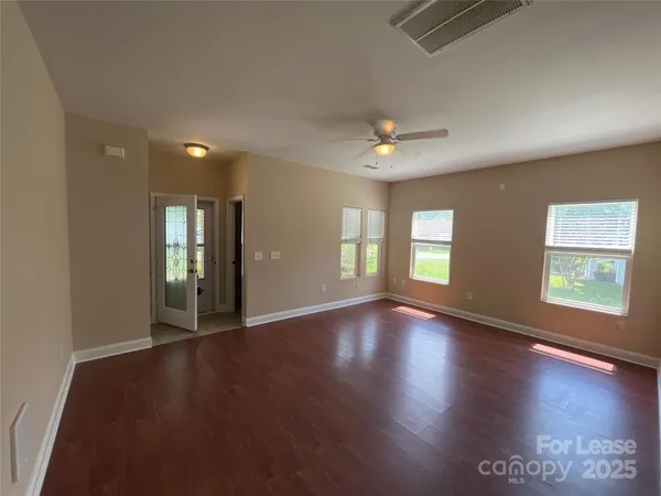 a view of an empty room with window and wooden floor