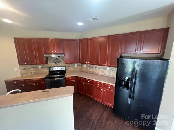 a kitchen with granite countertop a refrigerator stove and wooden cabinets