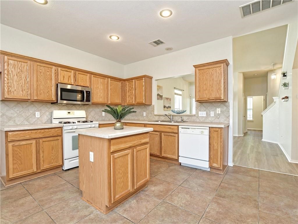 1117 Rawhide Trail Cedar Park, TX 78613 - Photo 11 of 36 a kitchen with stainless steel appliances granite countertop a stove top oven a sink dishwasher and a refrigerator with wooden cabinets
