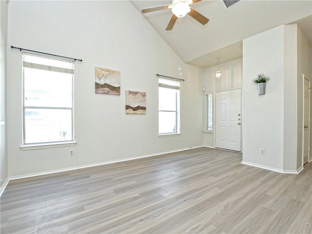 1117 Rawhide Trail Cedar Park, TX 78613 - Photo 8 of 36 an empty room with wooden floor chandelier fan and windows