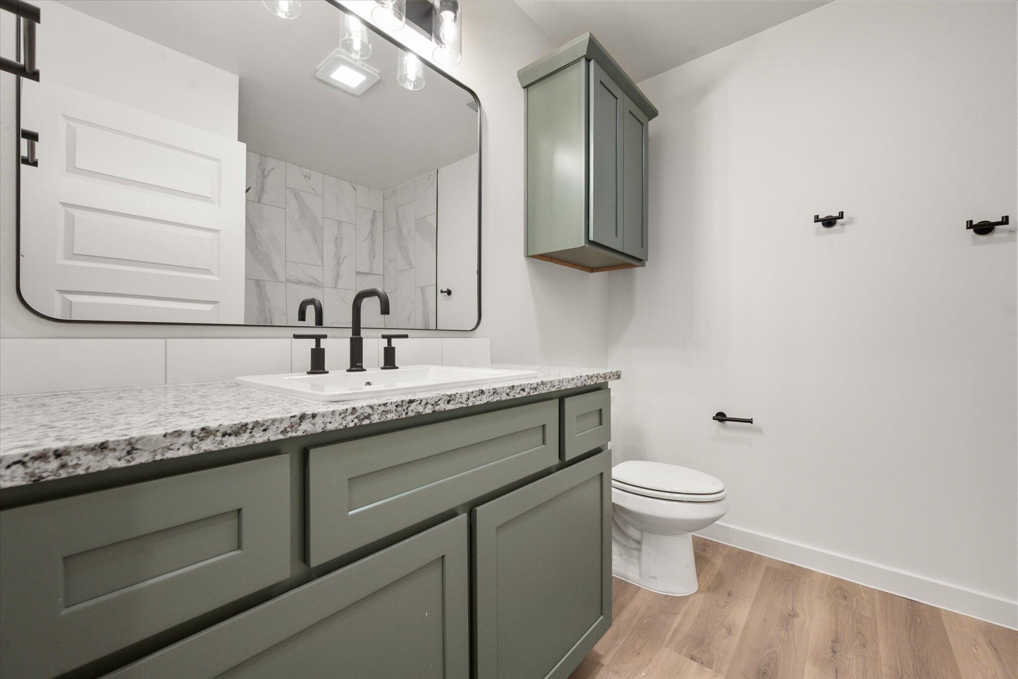 7006 56th Street Lubbock, TX 79407 - Photo 19 of 22 a bathroom with a granite countertop sink a toilet and a mirror