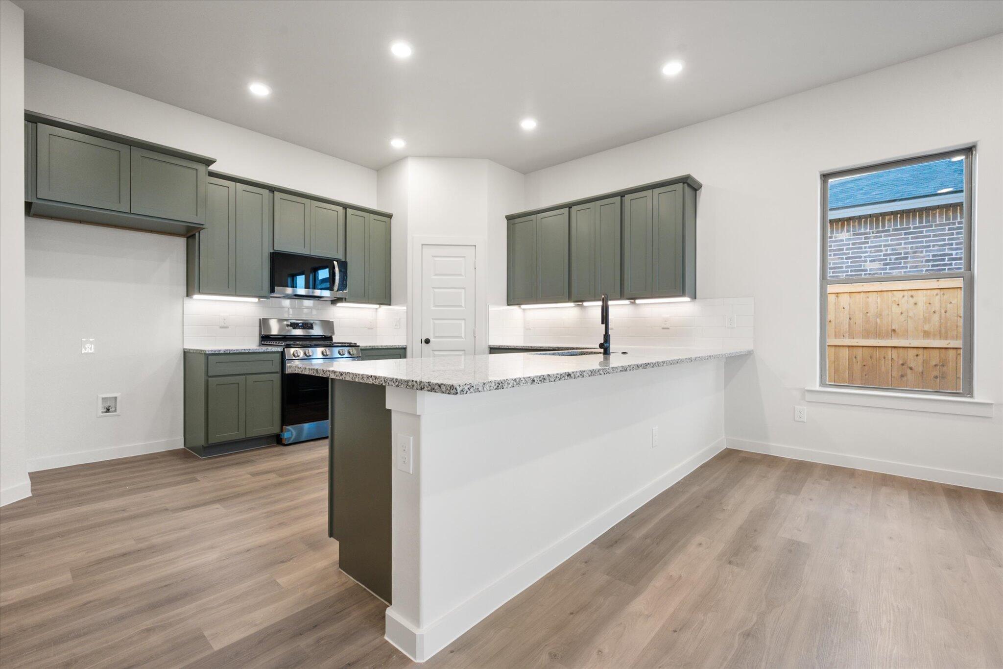 7006 56th Street Lubbock, TX 79407 - Photo 5 of 22 a kitchen with stainless steel appliances kitchen island granite countertop a stove a sink and a refrigerator