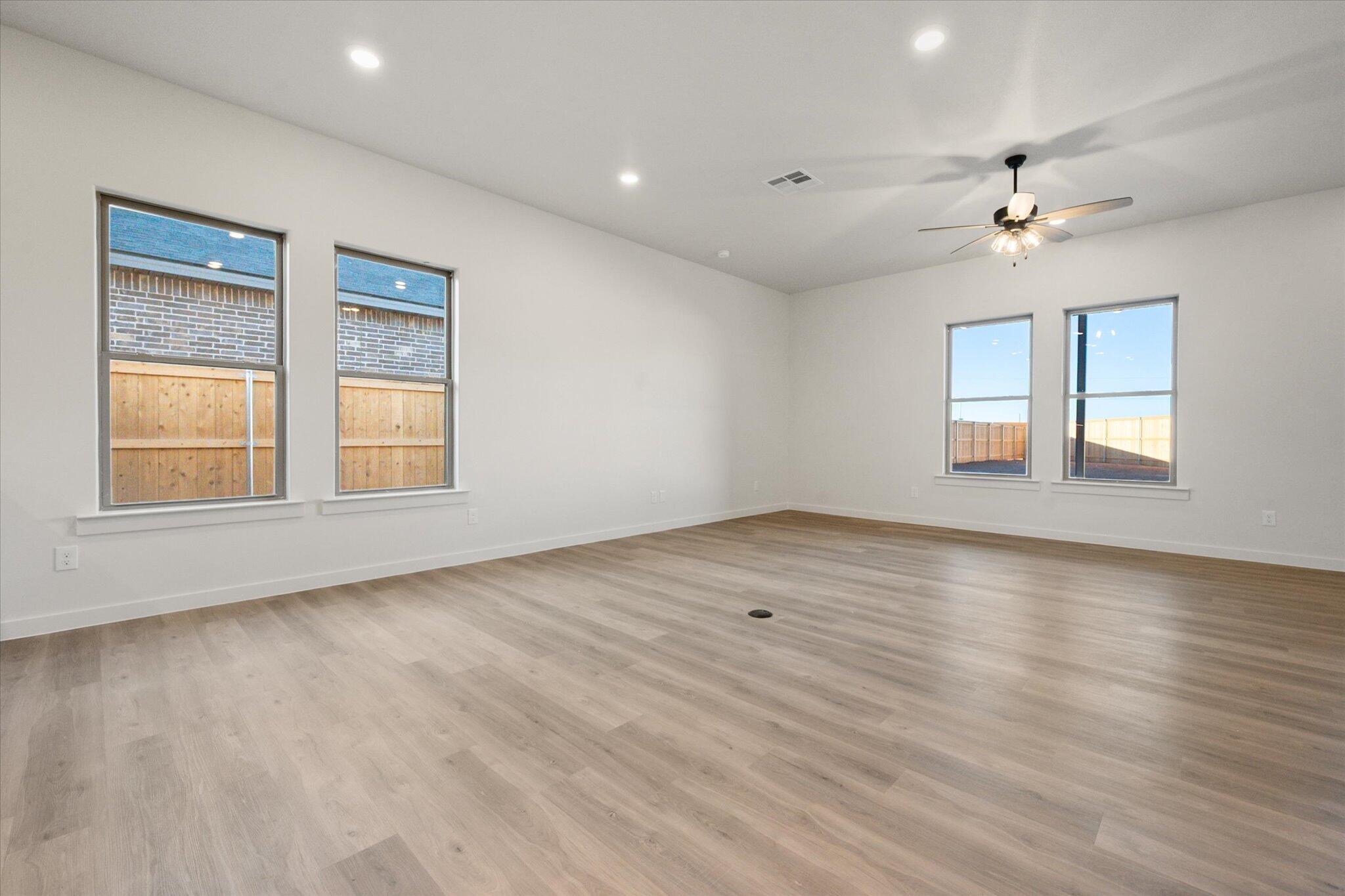 7006 56th Street Lubbock, TX 79407 - Photo 7 of 22 an empty room with wooden floor ceiling fan and windows