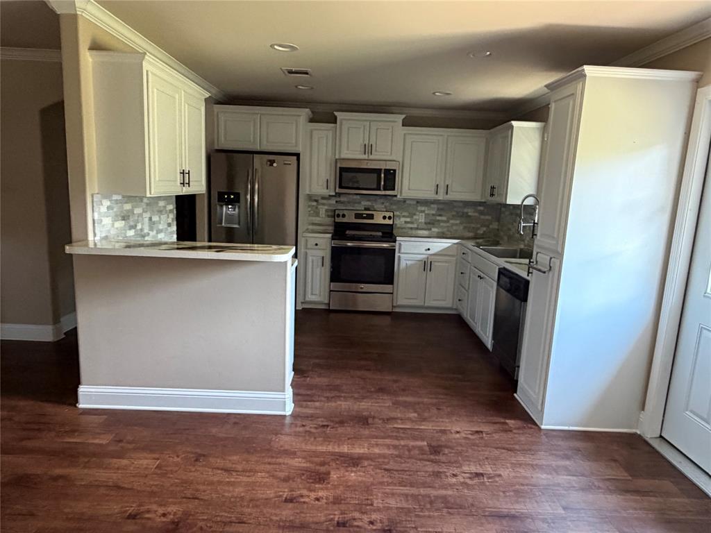 520 Big Red Circle Haughton, LA 71037 - Photo 6 of 25 Kitchen featuring white cabinetry, stainless steel appliances, a mosaic tile backsplash, wood-finish flooring, and a breakfast bar